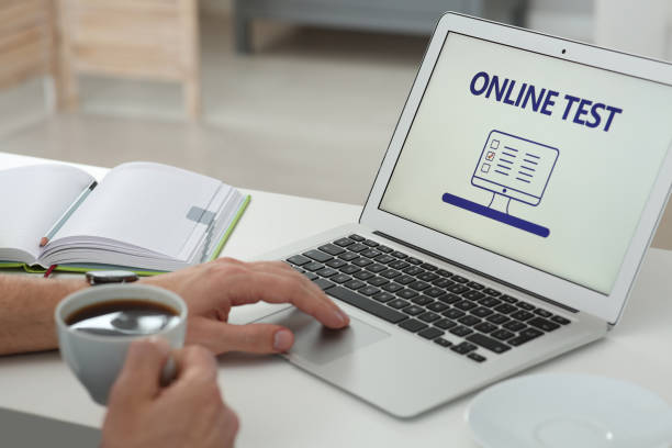 istock Man taking online test on laptop at desk indoors, closeup 1457064561