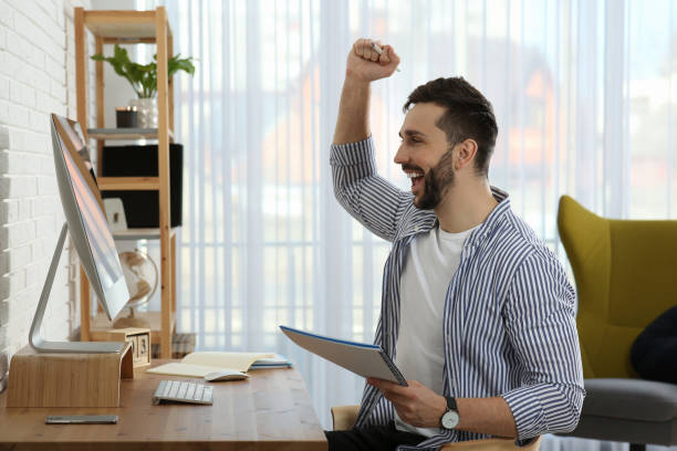 istock Online test. Happy man studying with computer at home 1457065141
