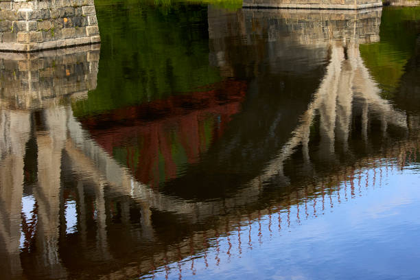 Reflection in the water of the old stone arch bridge