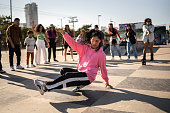 Young woman breakdancing during street party with her friends outdoors