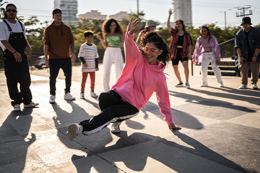 Young woman breakdancing during street party with her friends outdoors