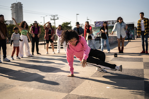 Young woman breakdancing during street party with her friends outdoors