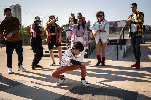 Child boy breakdancing during street party with her friends outdoors