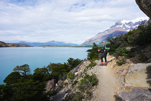mature latino hiker observing the landscape over the lake in the national park Torres del Paine