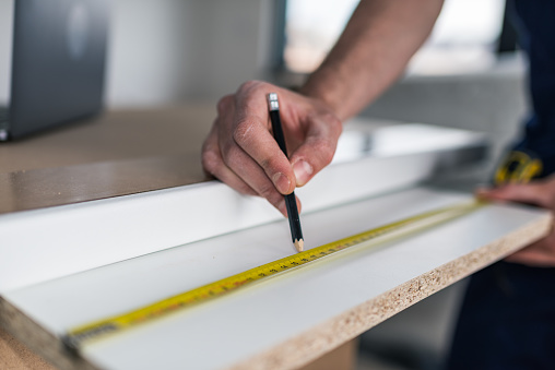 Manual worker measuring something while working on home renovation process.