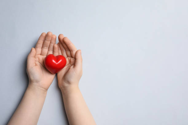 istock Child holding red heart on light grey background, top view. Space for text 1457073914