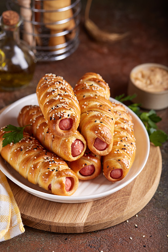 Sausages baked in a yeast dough cover. Pigs in a blanket. Fast food. Savory snack. Delicious homemade appetizer.
