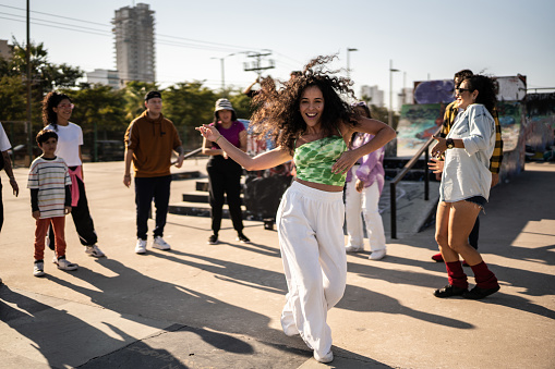 Retrato de una mujer adulta bailando reggaetón durante una fiesta callejera con sus amigos al aire libre photo