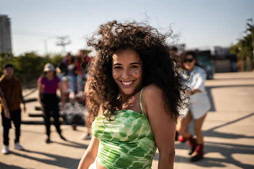 Portrait of mid adult woman dancing reggaeton during street party with her friends outdoors
