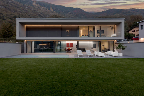 istock Frontal view modern house with swimming pool and garden illuminated by LED lights at sunset 1457080962