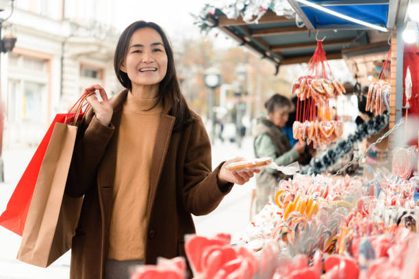 Portrait of a happy Asian woman in shopping buying candies on the street stock photo
