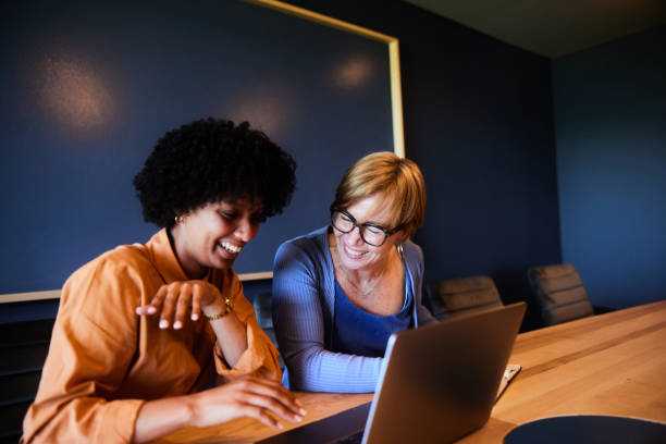 istock Diverse businesswomen laughing together while working in a board room 1457081234