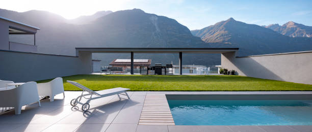 istock Panoramic view garden with pool of modern villa. There is a sitting area with armchairs, a deck chair, and at the back is the barbecue 1457081362