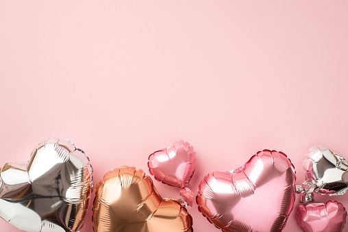 Valentine's Day celebration concept. Top view photo of heart shaped pink silver and golden balloons on isolated light pink background with copyspace