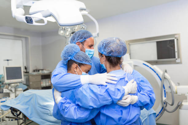 istock Medical professionals embracing each other in ICU. Doctors and nurses are in protective coveralls after successful treatment. They are at hospital during COVID-19. 1457082017
