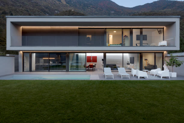 istock Frontal view modern house with swimming pool and garden illuminated by LED lights at dusk. 1457082032