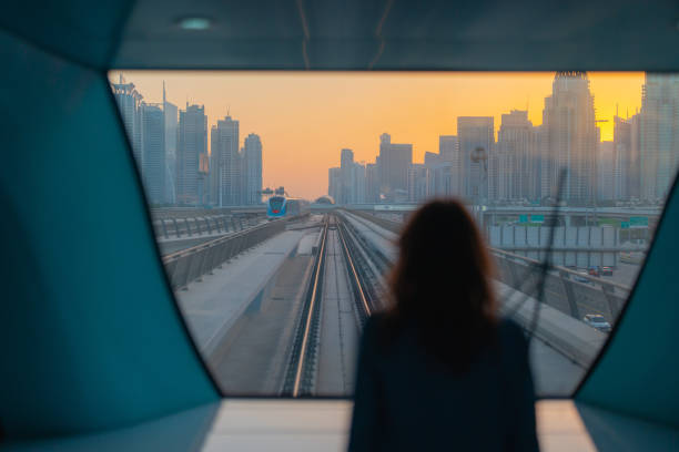 femme voyageant dans le métro de dubaï au coucher du soleil - looking at view railroad station street railroad track photos et images de collection