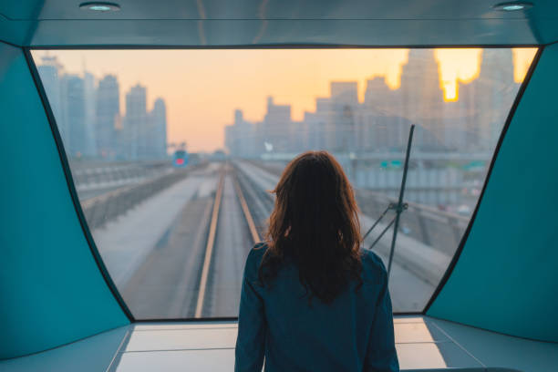 femme voyageant dans le métro de dubaï au coucher du soleil - looking at view railroad station street railroad track photos et images de collection