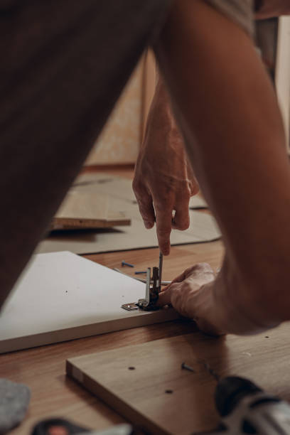 istock Unrecognizable man assembling furniture and using screwdriver in room at home 1457083337