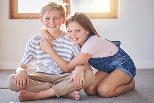Home, kids and hug of siblings or friends with youth fun and happiness together. Portrait of a girl and child bonding, smiling and hugging with friendship or sibling love on a house floor happy