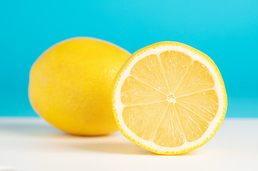 Whole and sliced lemon on blue background. Fresh yellow lemons on turquoise backdrop