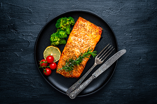 Healthy eating: overhead view of a baked salmon fillet with sesame seeds and vegetables. High resolution 42Mp studio digital capture taken with SONY A7rII and Zeiss Batis 40mm F2.0 CF lens