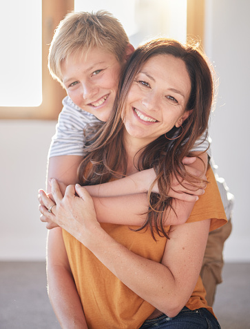 Mother, hug and kid in a family home together with happiness, bonding and parent care. Portrait of a mom and child in a house with love and happy child care smiling and hugging in a living room