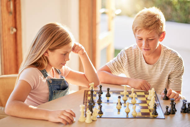 istock Children, chess and board game while thinking of move with knowledge, strategy and  planning to win for development and growth at home. Kids, siblings or boy and girl together for learning games 1457092809