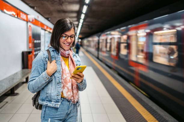 giovane donna che usa il telefono in una stazione della metropolitana - train subway station people subway train foto e immagini stock