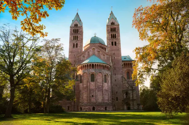 Famous cathedral in Speyer, Germany, called Speyerer Dom. The east side with park in autumn, framed by trees, lawn and blue sky