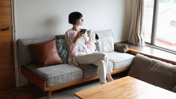 istock Young woman is looking at her phone while relaxing on the sofa 1457101377