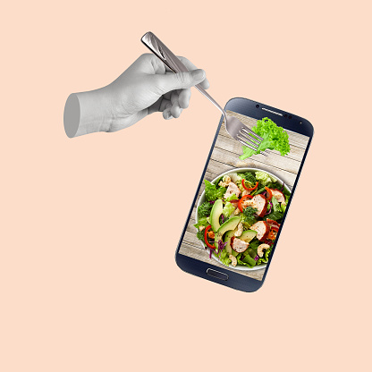 Contemporary art collage of hand holding fork with food and salad plate. The concept of diet and healthy nutrition. Concept of creativity and food online. Copy space for ad.