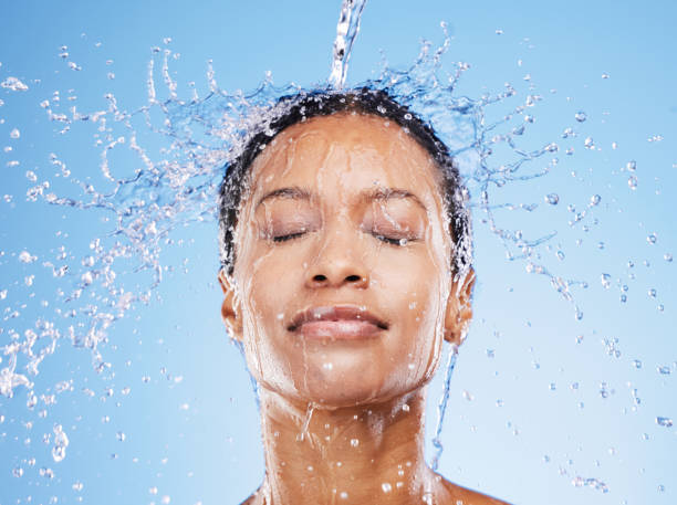 istock Beauty, water and splash with black woman and shower for hydration, moisture and spa luxury. Natural, fresh and hygiene with face of girl model and water drop for skincare, relax and self care 1457105607