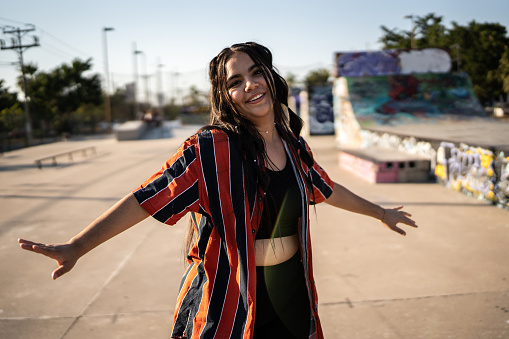 Portrait of a young woman dancing reggaeton at skateboard park
