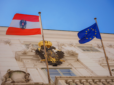 Ancient building with the flag of Austria and the European Union and the coat of arms of Austria. Summer Travel to capital of Austria Vienna.