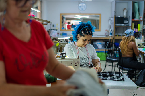 Latina women with an average age of 25 to 55 years old, seamstresses by profession, have a workshop in their workplace, repairing old vintage jeans on authentic sewing machines. Small family business, manufacture and repair of clothing, handmade, designer, tradition.