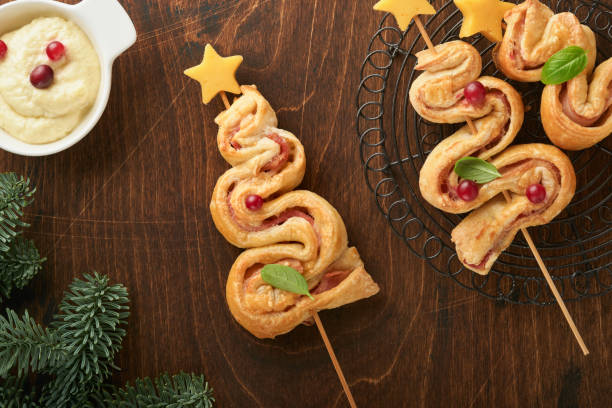 istock Christmas or New Year appetizer. Christmas tree shape puff pastry buns with cheese and ham. Group of Christmas tree shapes on wooden board. Festive idea for Christmas or New Year dinner. Top view. 1457112951