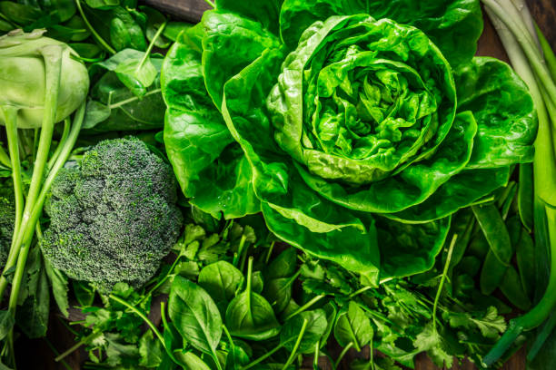 grünes bio-gemüse und dunkler blattnahrungshintergrund als gesundes ernährungskonzept - blattgemüse stock-fotos und bilder