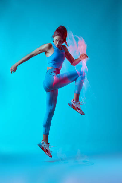 A fit sportswoman jumping and doing exercises. Long exposure capture movement.