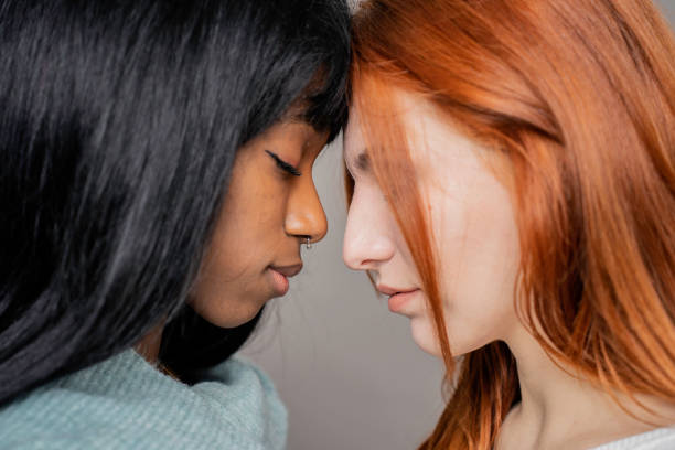 Couple of young lesbian women of different ethnicities head to head while looking down - Caucasian woman and African american girlfriend - Multicultural, Lgbtq and gay couple rights concept