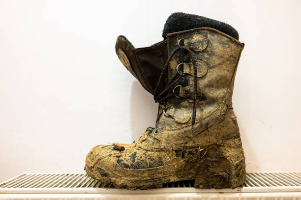 istock Trekking boots dirty in the mud drying on the radiator. 1457117442