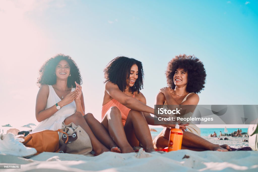 Friends, sunscreen and relax at beach, happy and summer holiday, travel and blue sky in Miami, happy and smile. Blaxk women, vacation and ocean vacation, happiness and afro with skincare and safety Beach Stock Photo