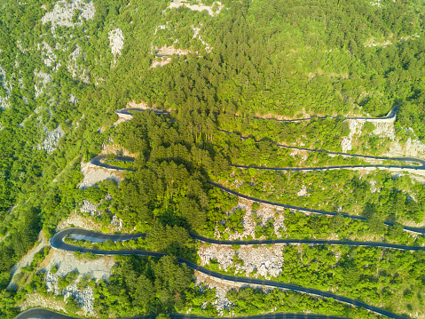 Incredible winding mountain road - Lovcensky serpentine with dangerous sharp extreme turns that leads to the top of mountain range of the Montenegrin mountains covered with green vegetation