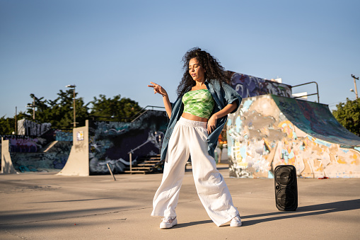 Mid adult woman dancing reggaeton at skateboard park