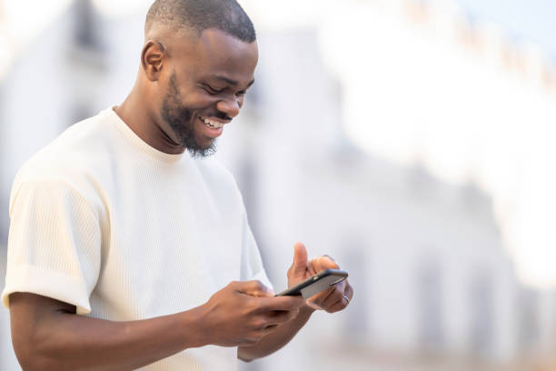 istock Cheerful man using mobile phone in the city with defocused background 1457121114
