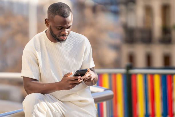 istock Cheerful man using mobile phone in the city with defocused background 1457121182