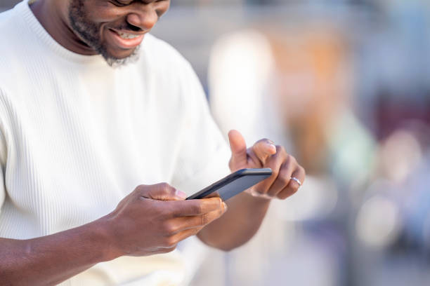 istock Cheerful man using mobile phone in the city with defocused background 1457121193