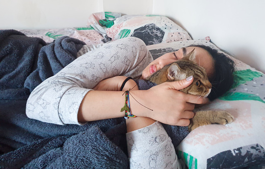 Relaxed woman and her cat sleeping together at home