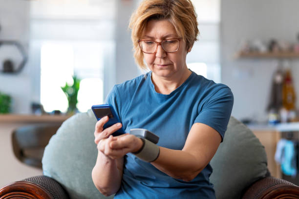 Home health monitoring and testing Woman checking blood pressure and using mobile app. blood pressure medication stock pictures, royalty-free photos & images