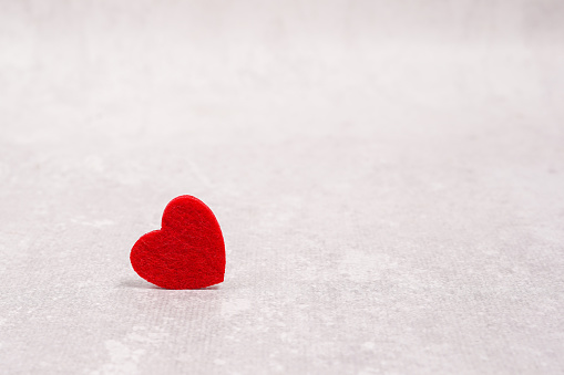 Red heart on light gray concrete background. space for text